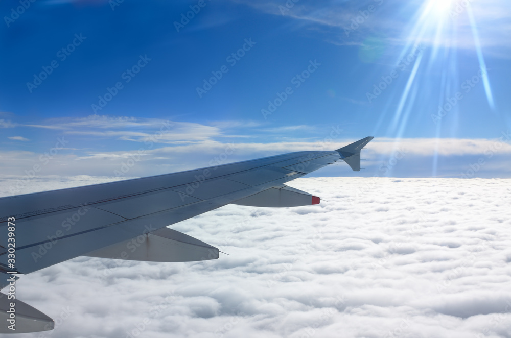 Obraz premium Flying above the clouds with aircraft wing and sun flare