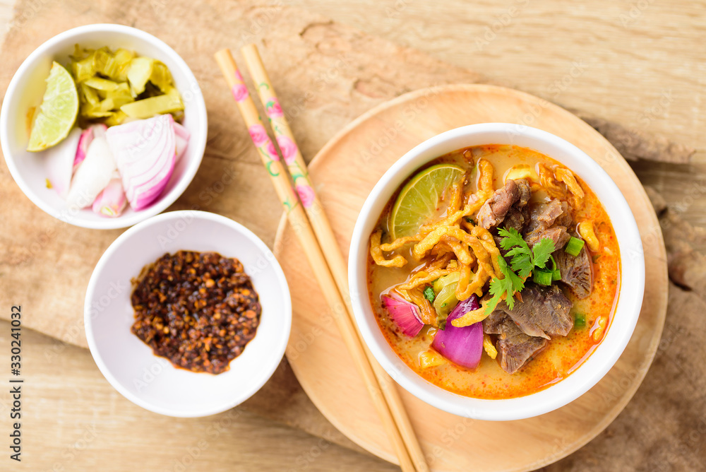 Traditional Northern Thai food (Khao Soi), spicy curry noodles soup with coconut milk and beef in a bowl, Top view