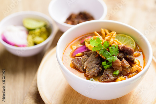 Traditional Northern Thai food (Khao Soi), spicy curry noodles soup with coconut milk and beef in a bowl