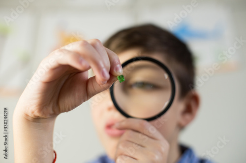 A cute kid looking through a magnifying glass