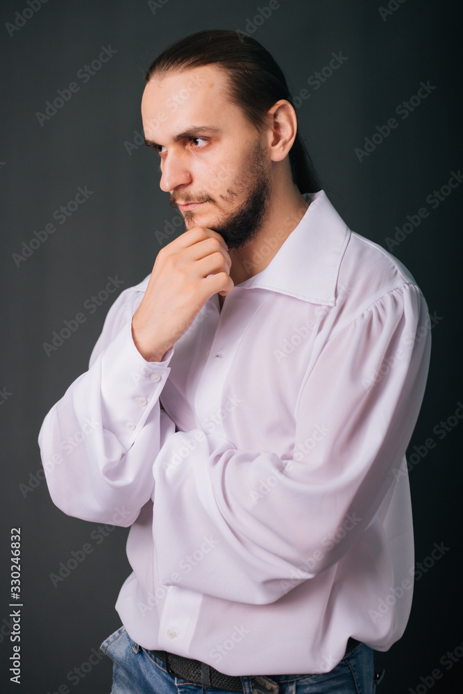 A guy with a beard in a white vintage shirt. Romantic portrait on a gray background A guy with a beard in a white vintage shirt. Romantic portrait on a gray background