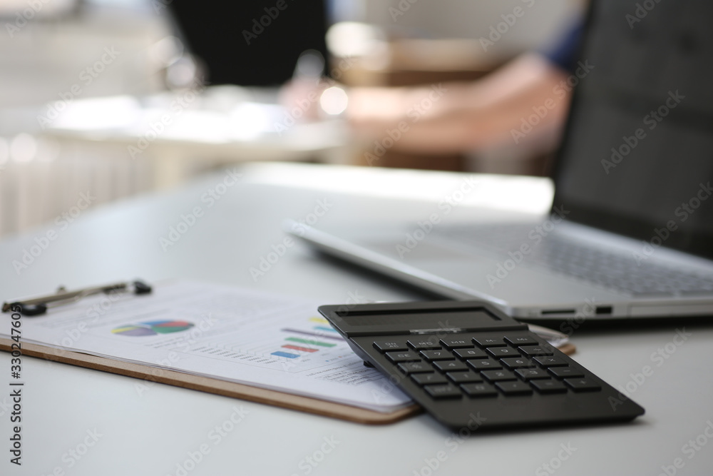 Black calculator and financial statistics on clipboard pad at office table closeup. Internal Revenue Service inspector sum check, irs investigation, earnings, savings, loan and credit concept Black calculator and financial statistics on clipboard pad at office table closeup. Internal Revenue Service inspector sum check, irs investigation, earnings, savings, loan and credit concept