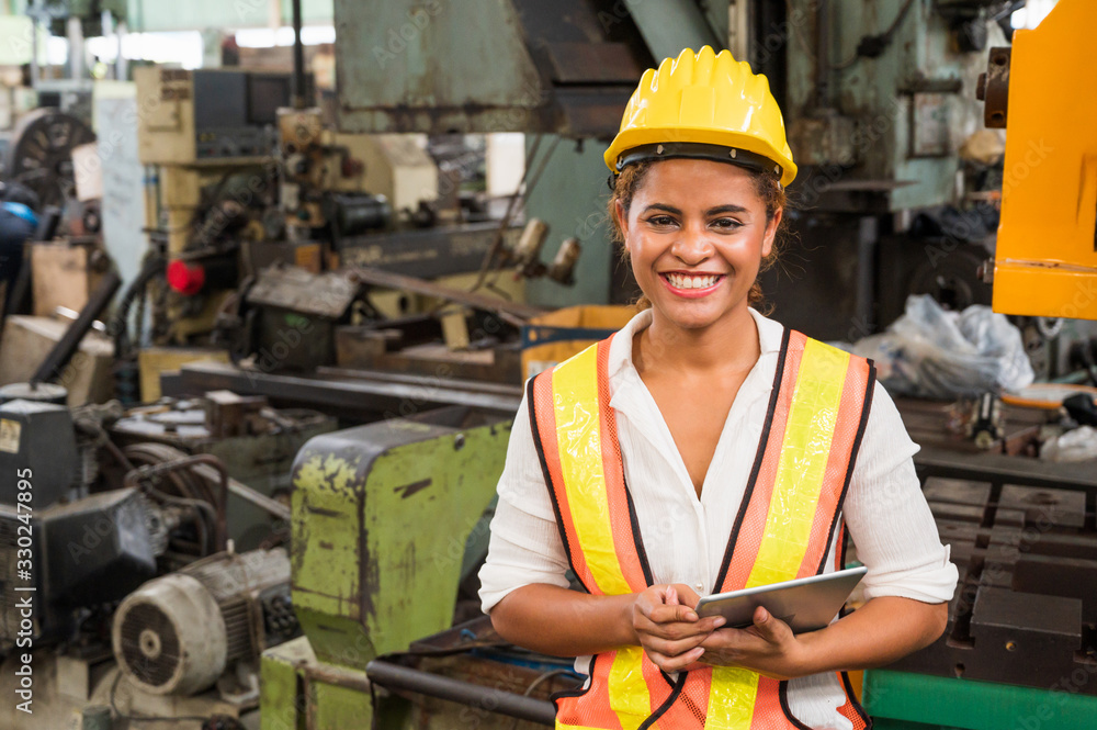 Female industrial worker working and checking machine in a large industrial factory with many equipment. Female industrial worker working and checking machine in a large industrial factory with many equipment.