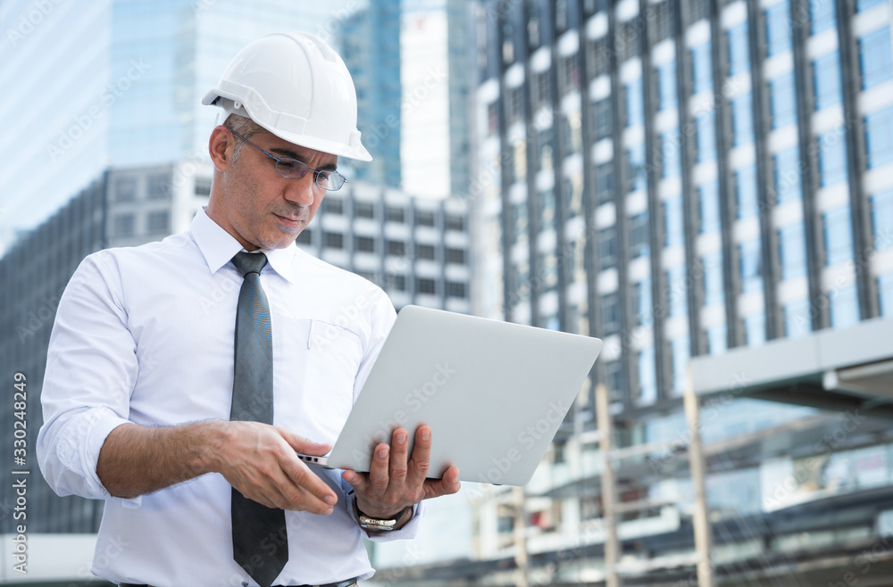 Civil engineering using laptop while working on building construction site.