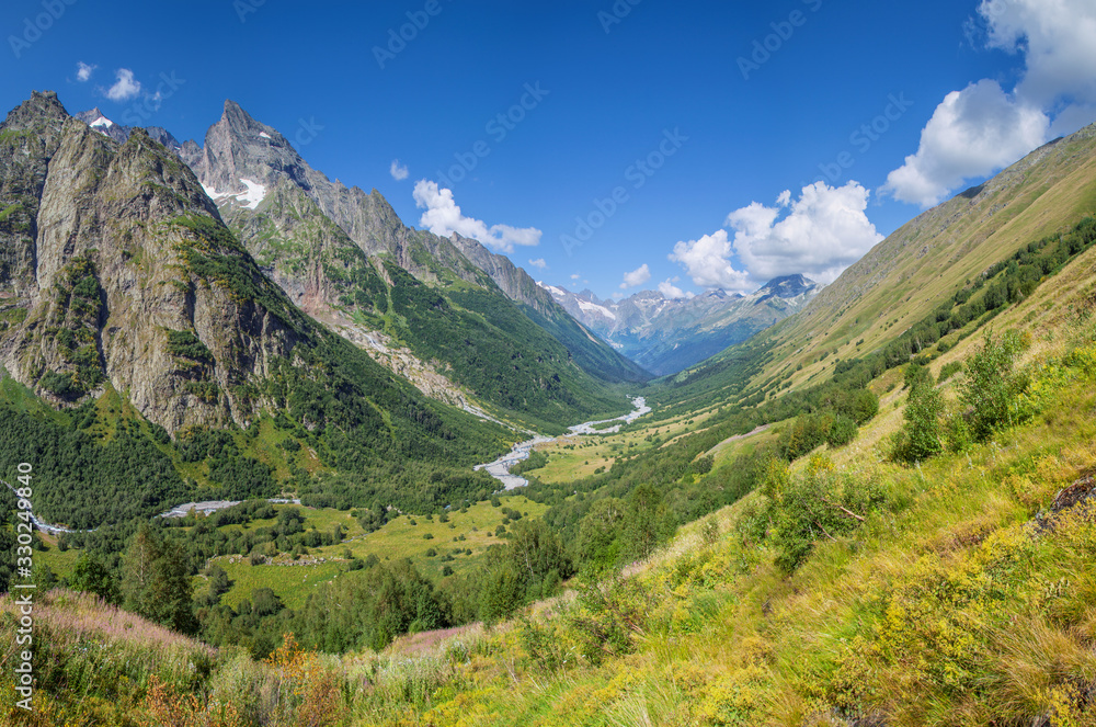 Scenic mountain valley in the Caucasus Mountains, summer greens and snow-capped peaks