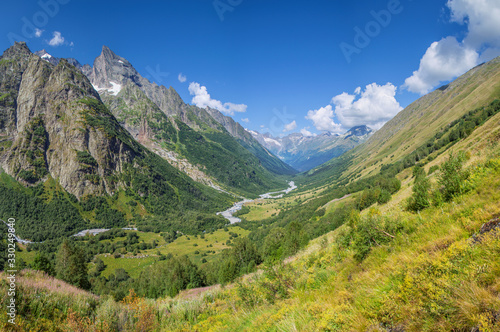 Scenic mountain valley in the Caucasus Mountains, summer greens and snow-capped peaks © Valerii