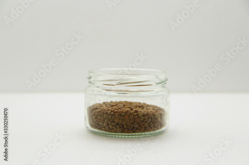 Glass jar with lentils on a white background, side view.