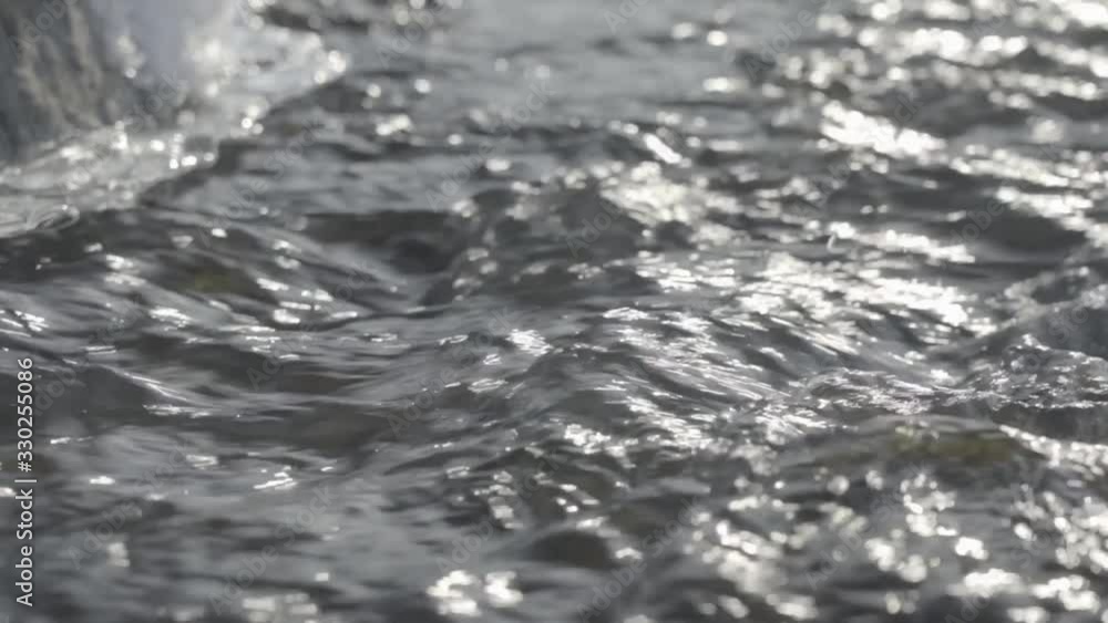 Fast moving water, passing by melting ice. Close-up. Stream in a snowy forest. S-Log