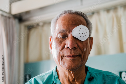 patient covering eye with protective shield after eyes cataract surgery in hospital