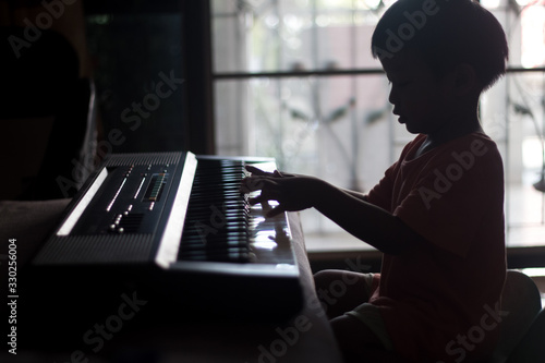 silhouette little boy take electric piano