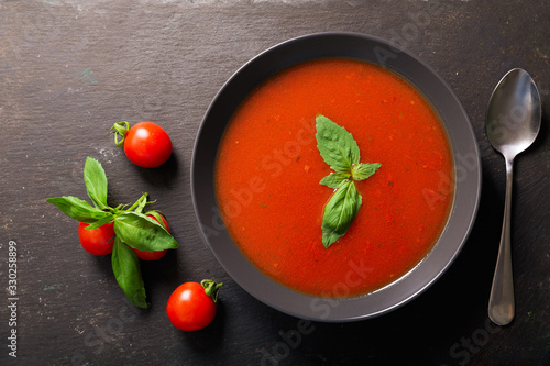 Photos bowl of tomato soup with basil on dark background