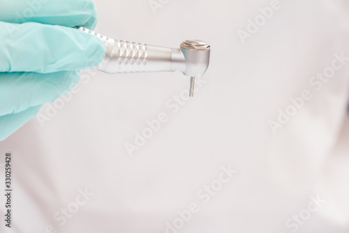 Dentist's hand in glove with dental handpiece.