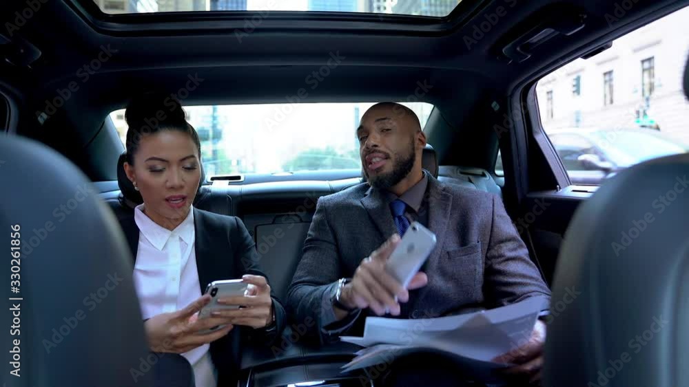 Happy diverse man and woman in formal wear sitting in transport and communicating about financial news read on mobile website for investors, business people getting to destination in executive car Happy diverse man and woman in formal wear sitting in transport and communicating about financial news read on mobile website for investors, business people getting to destination in executive car