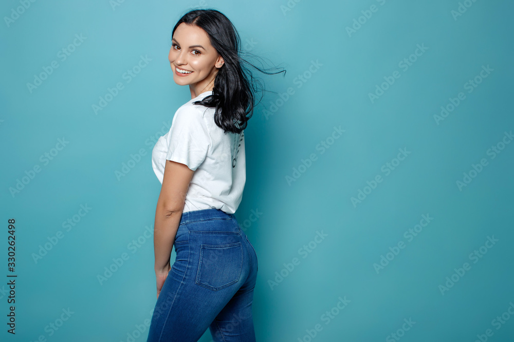 Young woman in the studio on a blue background conveys different emotions. Beautiful woman in jeans and a white t-shirt. Young woman in the studio on a blue background conveys different emotions. Beautiful woman in jeans and a white t-shirt.