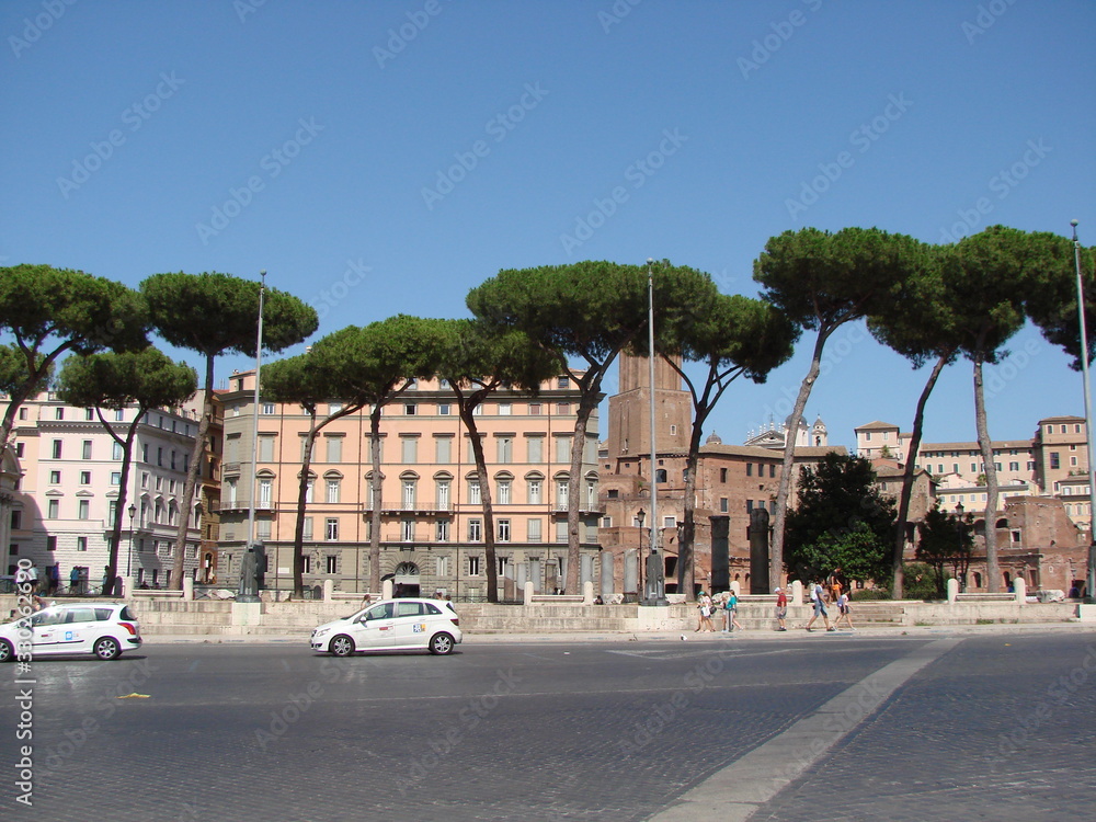 shrubs at the foot, and against the backdrop of cloudy summer sky. The cityscape is decorated with Italian pine on the background of the morning blue sky.