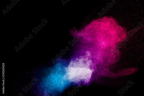 Multicolored powder explosion on black background.Color dust splash cloud on dark background.Launched colorful particles.