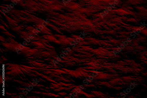 Rugged maroon surface with bulges and shadows. Maroon background with glare and dimming