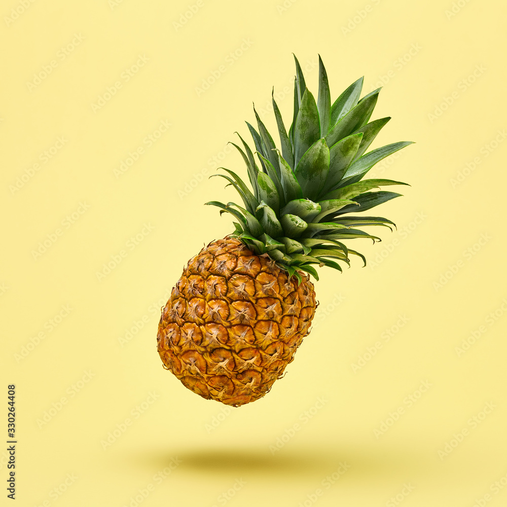 Flying in air pineapple tropical fruit on yellow. Minamal, Vitamin pineapple, vegan dieting food. Whole sweet fresh fruit. Levitation, falling fly pineapple creative concept