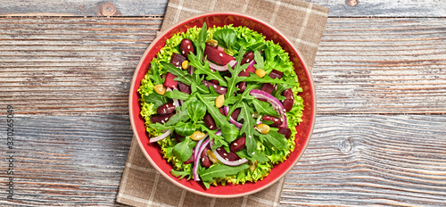 Vegan beetroot salad with red bean, lettuce, arugula, sunflower, sesame seed. Home made vegetarian beet mix leaves salad on wood background. Tasty beetroot diet dish. Top view.