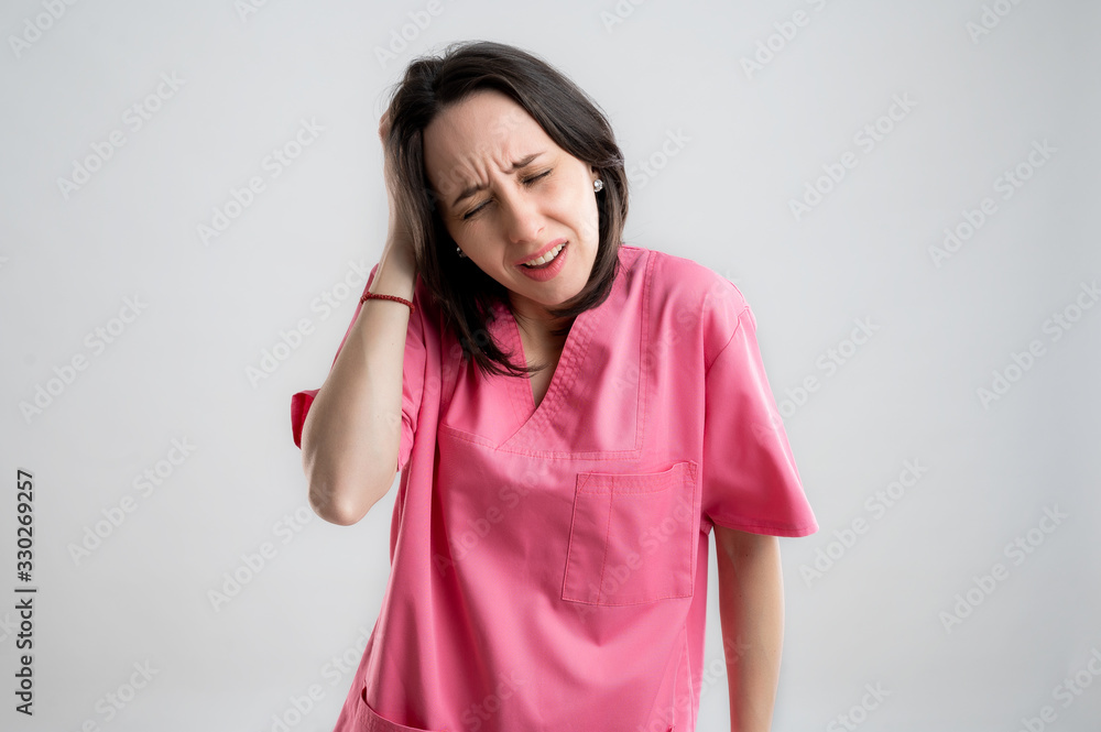 Young woman medical professional nurse or doctor dressed with pink hospital clothes has headache Young woman medical professional nurse or doctor dressed with pink hospital clothes has headache