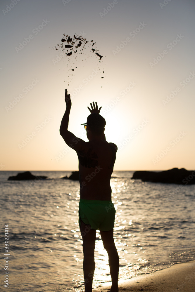 Hombre joven en la playa con gafas de sol y gorra disfrutando de la costa mediterránea de Cadiz, España