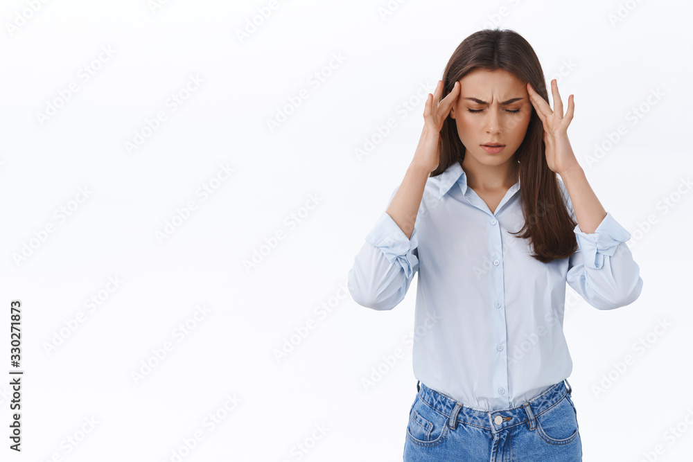 Ugh worst headache ever. Hardworking woman suffer huge migraine, feeling pain in head, massaging temples and close eyes frowning as cant focus on work, stand uneasy over white background Ugh worst headache ever. Hardworking woman suffer huge migraine, feeling pain in head, massaging temples and close eyes frowning as cant focus on work, stand uneasy over white background