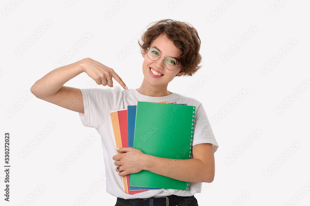 Female student in a white shirt and eyeglasses pointing at colorful folders Female student in a white shirt and eyeglasses pointing at colorful folders