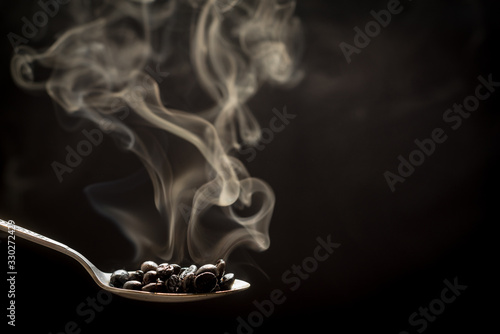 Smoke and roasred seeds,Coffee beans in spoon, close up