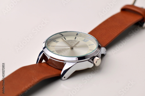 Silver wrist watch with a brown single-piece leather strap. Double-sided nato strap. White background.