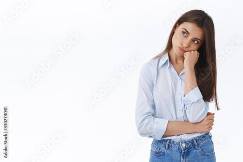 Bored and sad cute young girlfriend waited all day for boyfriend present, leaning on palm looking gloomy and displeased, stare left offended, sulking from insult, standing upset white background © Cookie Studio