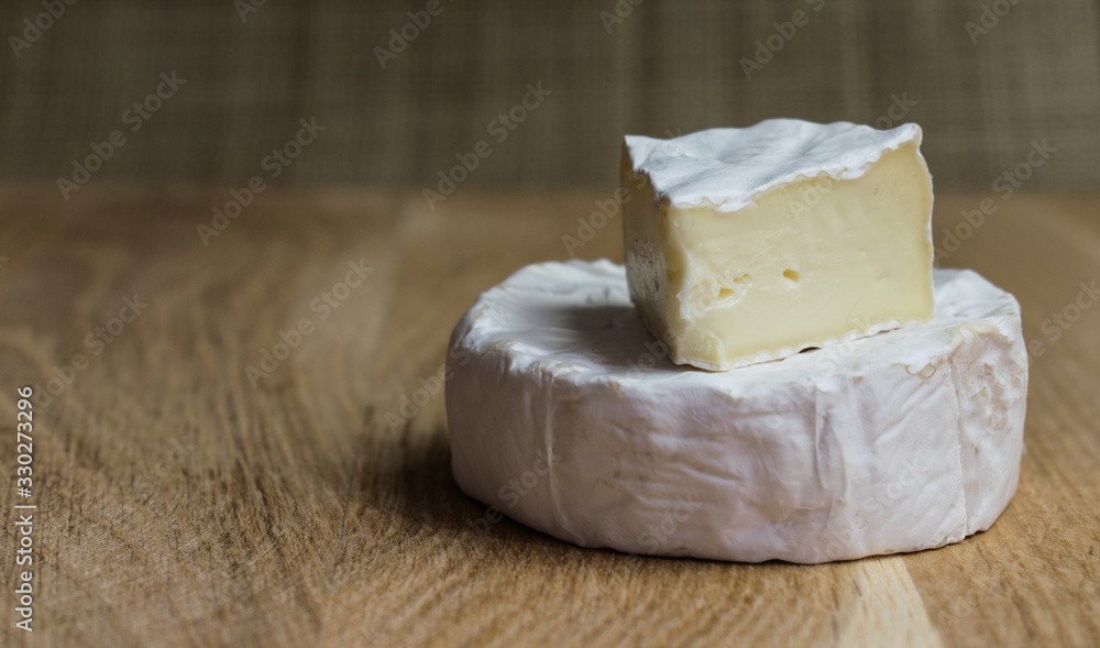 Camembert soft cheese on light wood background