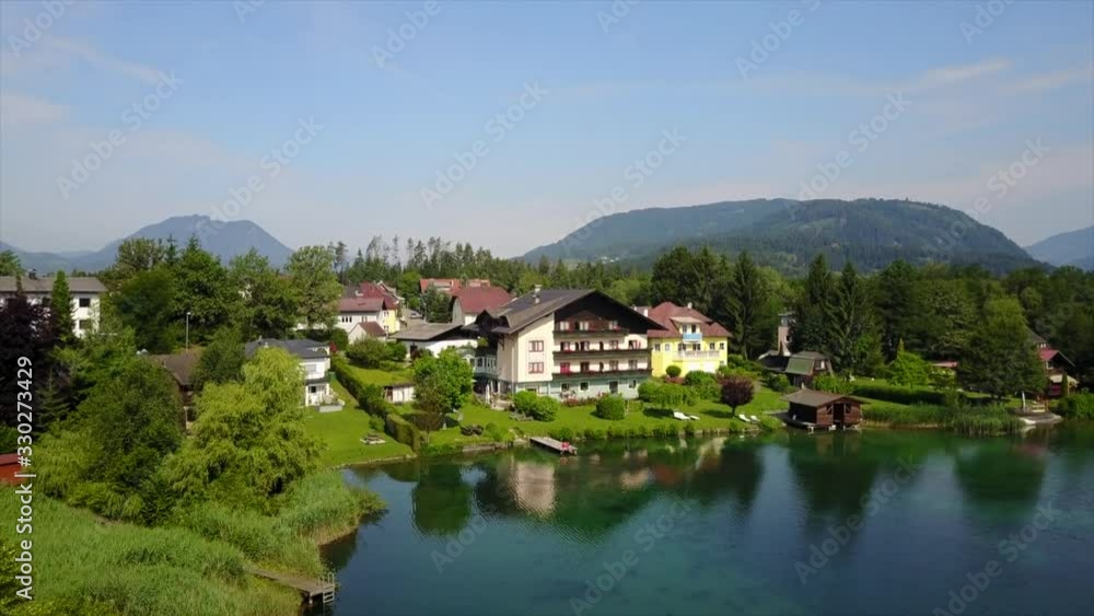 Aerial photography of a large beautiful house by the lake surrounded by other houses and green hills Aerial photography of a large beautiful house by the lake surrounded by other houses and green hills