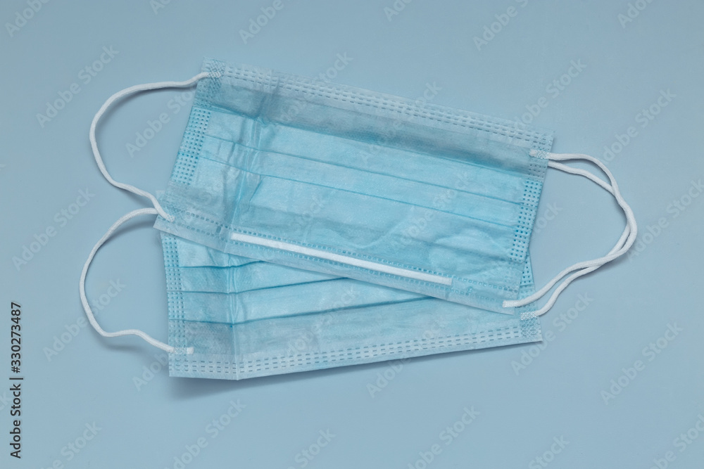 Surgical mask with rubber straps. A three-layer surgical mask for covering the mouth and nose. Bacterial mask procedure. Concept of protection. Surgical mask with rubber straps. A three-layer surgical mask for covering the mouth and nose. Bacterial mask procedure. Concept of protection.