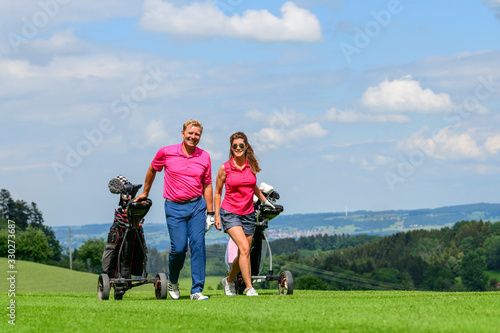 Paar gutgelaunt unterwegs auf einem Golfplatz