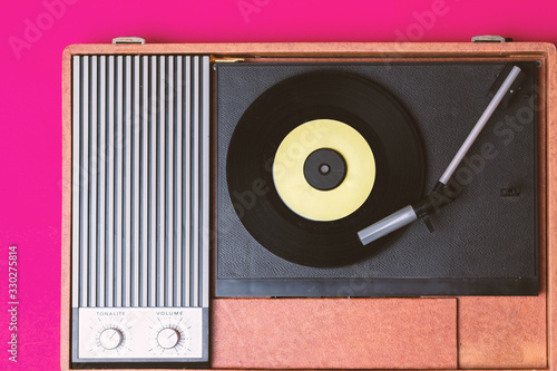 Retro vinyl player and turnable on a fuchsia background. Entertainment 70s. Listen to music. Top view. photo