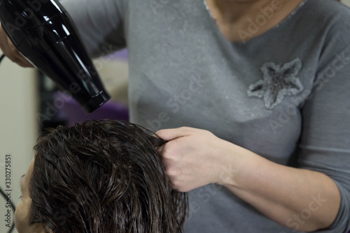 Beauty concept - Professional hairdresser applying shampoo, washes color paint off and massaging hair of a customer. Woman having her hair washed in a hairdressing beauty salon