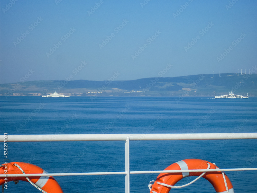 Plastic orange lifebuoy aboard a ferry ship in the blue sea