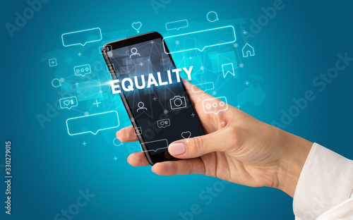 Female hand typing on smartphone with EQUALITY inscription, social media concept