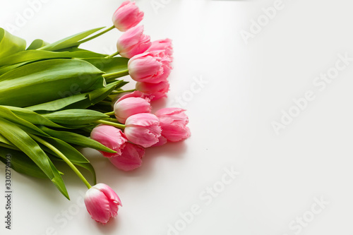 Fototapeta Naklejka Na Ścianę i Meble -  pink tulips lie on a white table next to colored pens