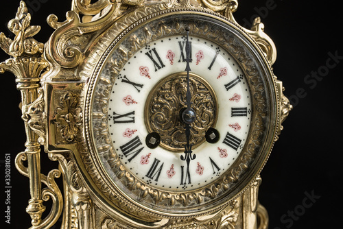 dial of vintage bronze clock on black background, antique clock photo close up, old bronze clock in gilding, six o'clock on the dial