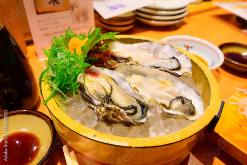 Fresh raw oysters on ice in wooden bowl