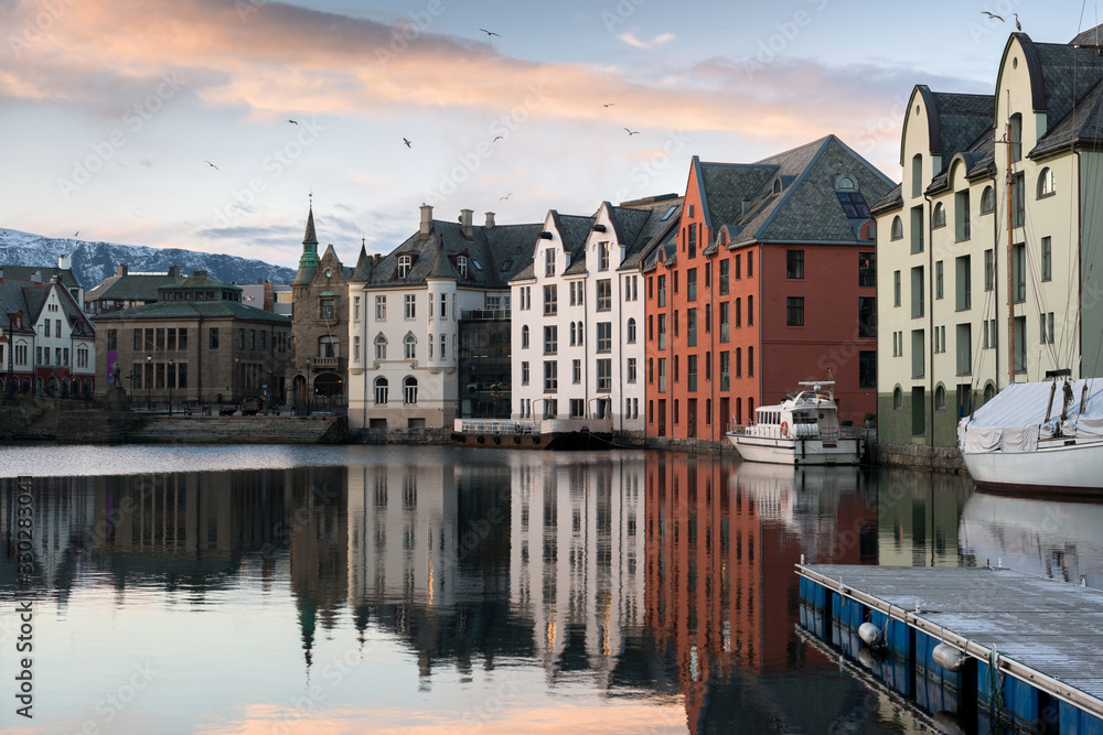 A sunset photograph of beautiful buildings reflecting off the water, taken in Aalesund, Norway.