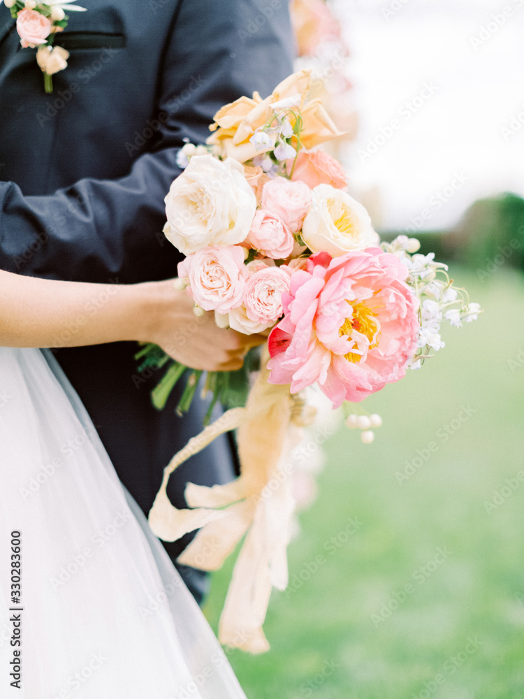 Beautiful wedding bouquet in hands of the bride. Just married wedding couple posing and bride holding in hands bouquet