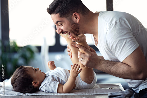 Photographie Smiling young father has fun with little baby while changing his nappy at home