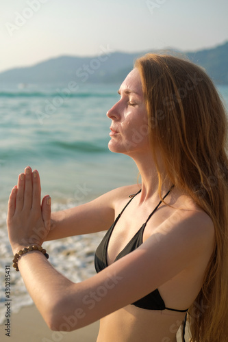 A young woman is practicing yoga on the ocean.
