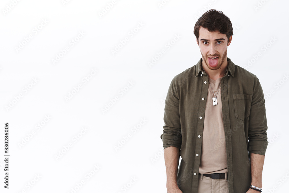 Emotions and people concept. Portrait of disgusted young man, showing aversion and dislike, want puke as seing someone bad taste, show tongue from disgust standing white background upset