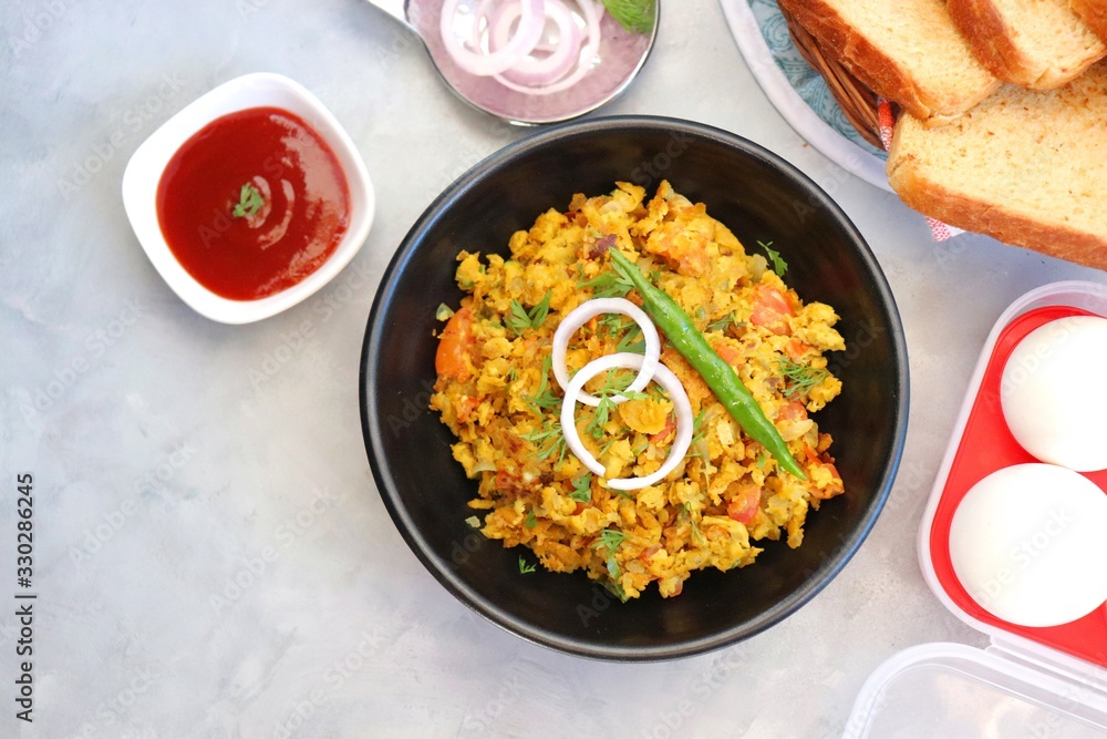 Indian Breakfast Dish - Parsi Akuri or Anda Bhurji or Indian spicy scrambled eggs served with toasted brown bread & ketchup. Famous Indian street food. Ingredients background with copy space. Indian Breakfast Dish - Parsi Akuri or Anda Bhurji or Indian spicy scrambled eggs served with toasted brown bread & ketchup. Famous Indian street food. Ingredients background with copy space.