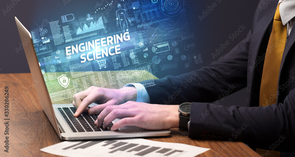 Businessman working on laptop with ENGINEERING SCIENCE inscription, cyber technology concept Businessman working on laptop with ENGINEERING SCIENCE inscription, cyber technology concept