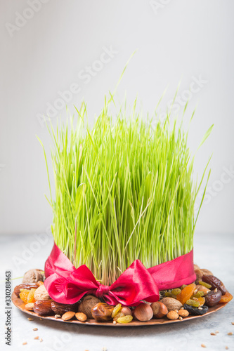 Happy Nowruz holiday background. Celebrating  various dried fruits, nuts, seeds, light background with green grass wheat, copy space top view photo