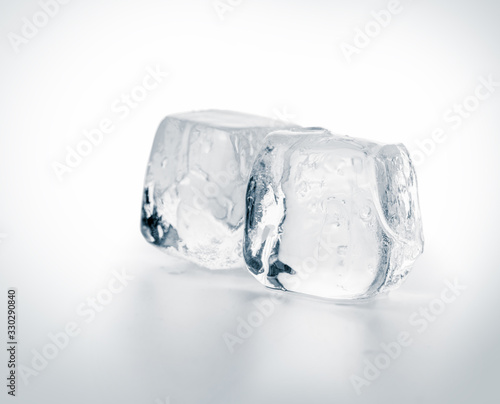 Two natural crystal clear melting ice cubes on white background.